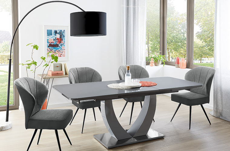 Modernes Esszimmer mit grauem Tisch und vier Stühlen.