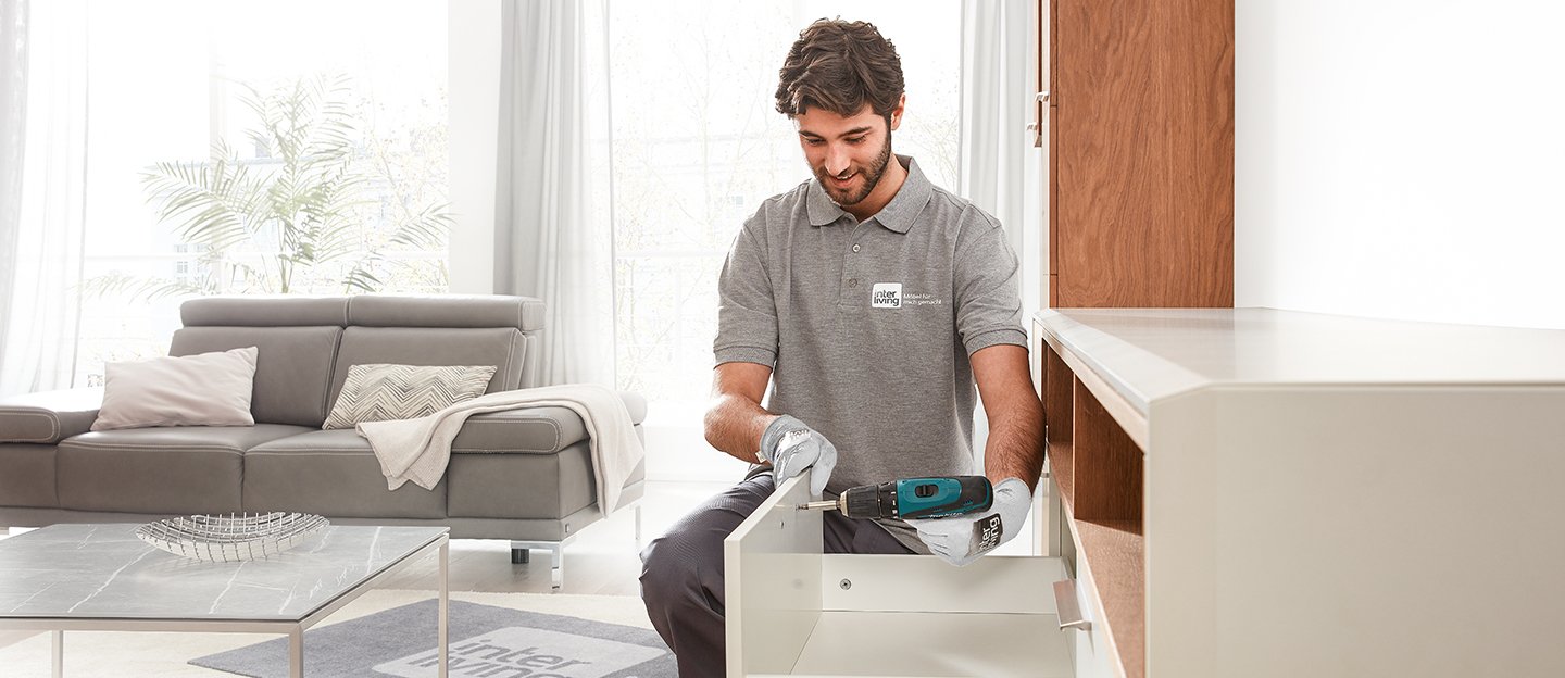 Monteur beim Aufbau eines Schranks in einem hellem Raum.