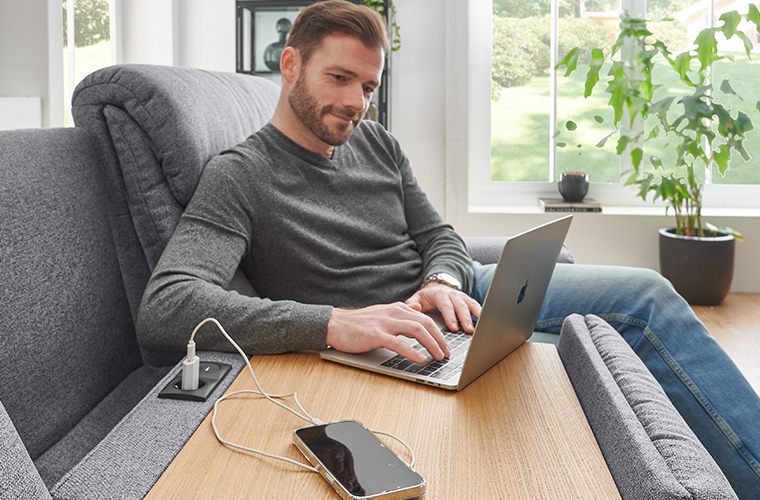 Frau entspannt sich auf grünem Interliving Sofa mit Kopfstütze.