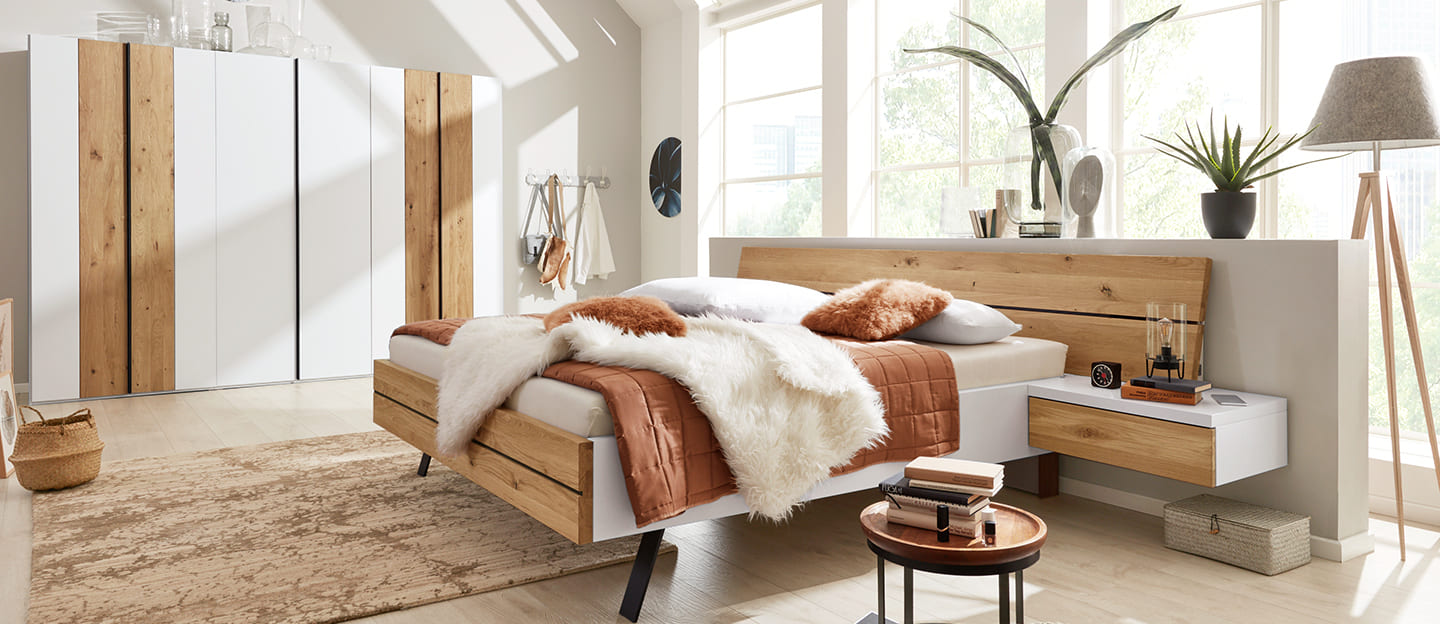 Frau entspannt sich in einem hell bezogenem Bett.