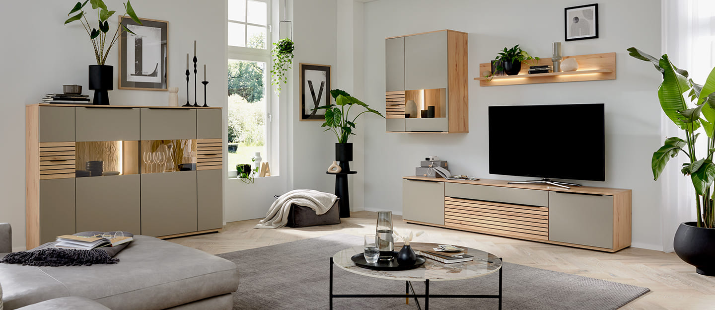 Wohnwand von Interliving in Holzoptik mit schwarzem Akzent in hellem Raum.