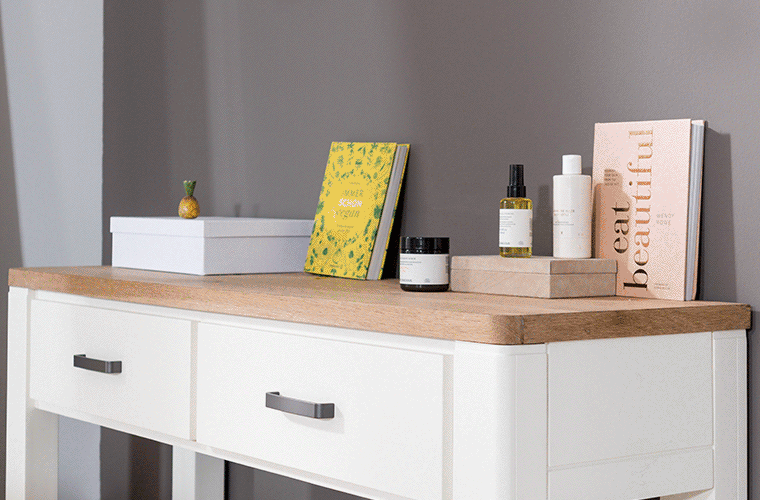 Ein weiß lackierter Konsolentisch mit Eichenholzplatte von RIVIÈRA MAISON, welcher dekoriert ist.