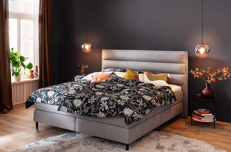 Polsterbett in Grau mit gemusterter Bettwäsche von SCHÖNER WOHNEN.