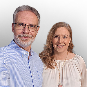 Inhaber von Möbel Janz Rücken an Rücken vor grauer Wand.