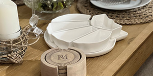 Verschiedene weiße Geschirrteile und eine Kerze auf einem holz Untergrund.