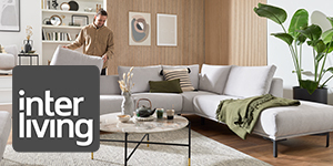 Mann richtet sein hellgraues Sofa in einem hellen Wohnzimmer. In der linken Ecke unten ist das Interliving Logo zu sehen.