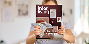Eine Person hält das neue Interliving Magazin in die Kamera.