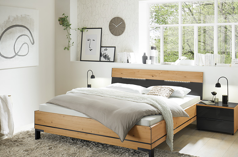 Helles Schlafzimmer mit Doppelbett, welches Holzdetails hat.
