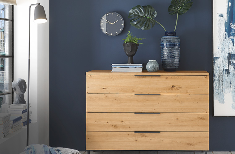 Große Kommode aus Holz vor einer blauen Wand.