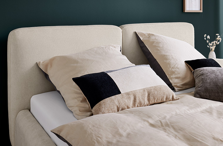 Nahaufnahme von Zierkissen auf einem hellen Doppelbett.