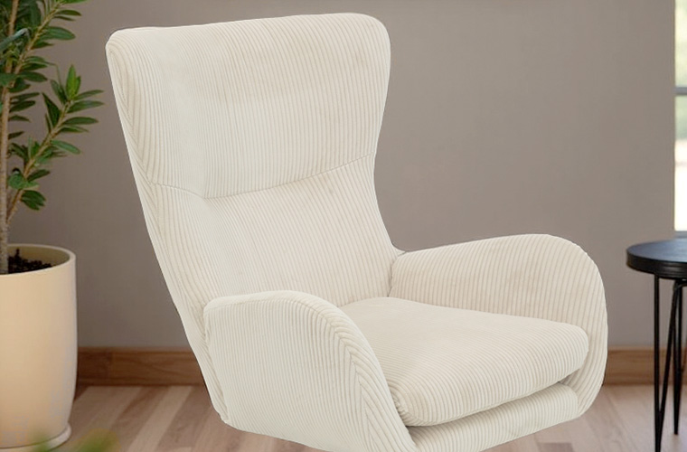 Ein hoher, beigefarbener Ohrensessel, der vor einer hellen Wand steht.