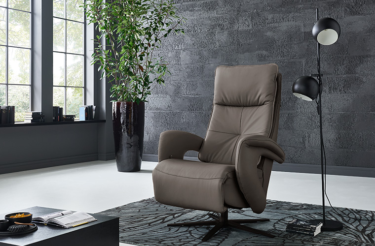 Dunkelbrauner Relaxsessel mit Fußstütze in einem modernen Wohnzimmer.