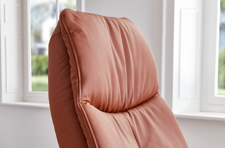 Detailaufnahme einer orangen Lederpolsterung eines Sessels.