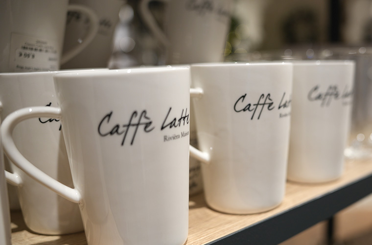 Reihe von weißen Keramiktassen mit dem Schriftzug "Caffè Latte" an der Seite.