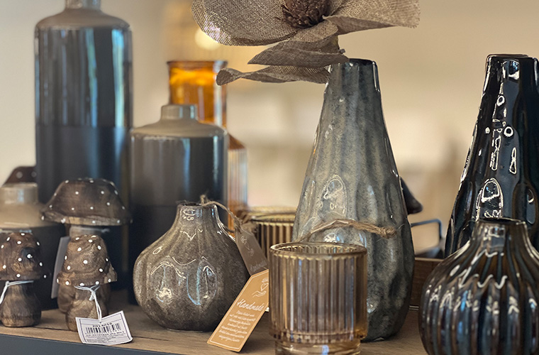 Verschiedene Dekorationsartikel, wie z. B. getönte Glasflaschen oder Vasen und metallische Objekte.