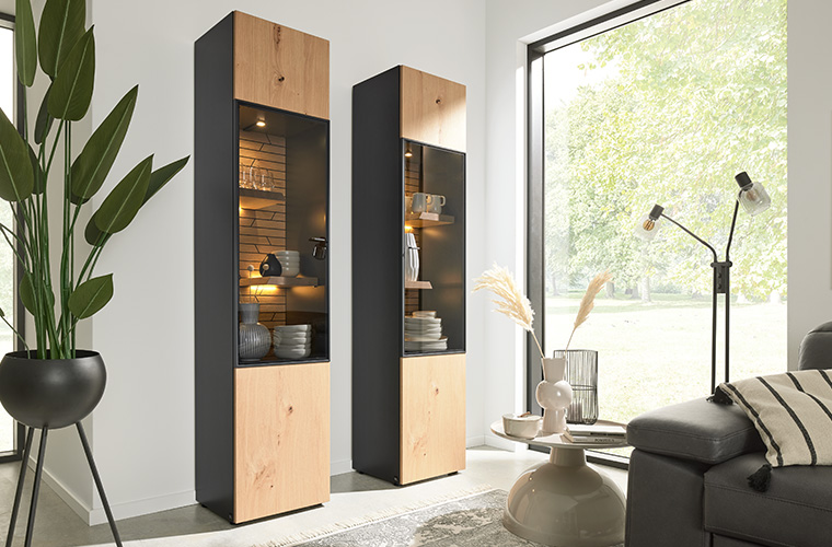 Essbereich mit einem hohen, beleuchteten Vitrinenschrank aus dunklem Holz und Glas.