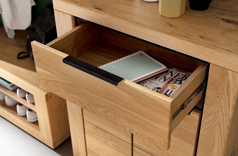 Geöffnete Schublade eines Garderobenschranks aus hellem Holz.