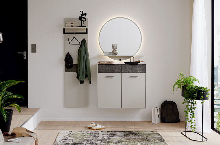 Ansicht einer weißen Garderobenkombination mit einem runden, beleuchteten Spiegel.