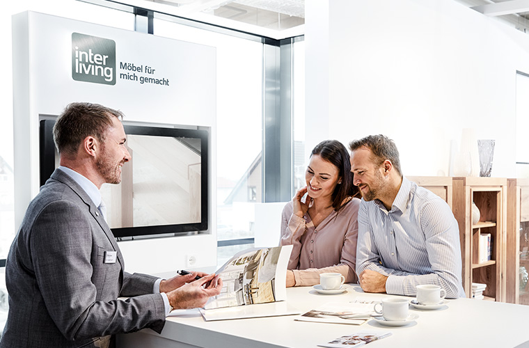 Verkäufer berät in einem Möbelhaus ein Paar.