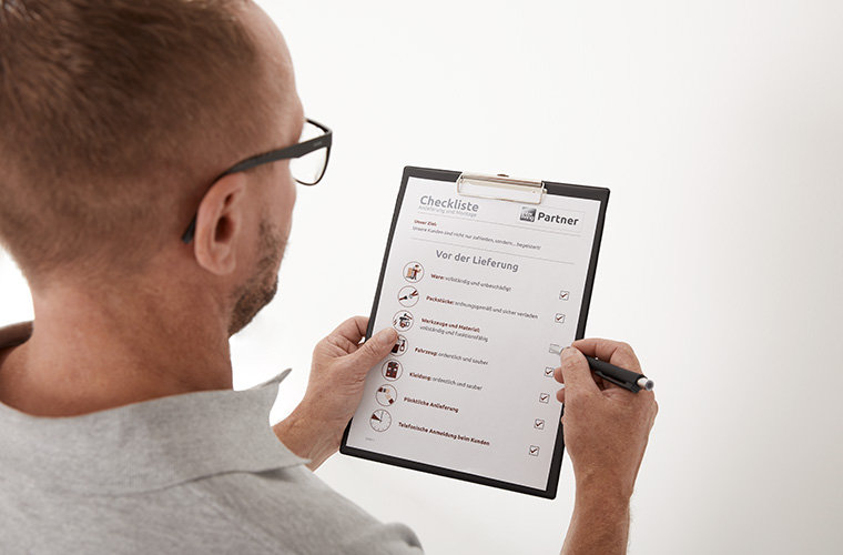 Ein Monteur prüft eine Checkliste.
