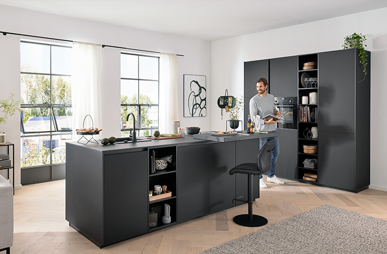 Wohnküche in Schwarz mit einer Kochinsel in der Mitte.