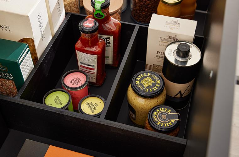 Geöffnete Schublade eines Küchenschranks mit Gewürzen und Flaschen.