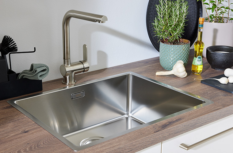 Edelstahlspüle mit modernem Wasserhahn in einer Küchenarbeitsplatte.