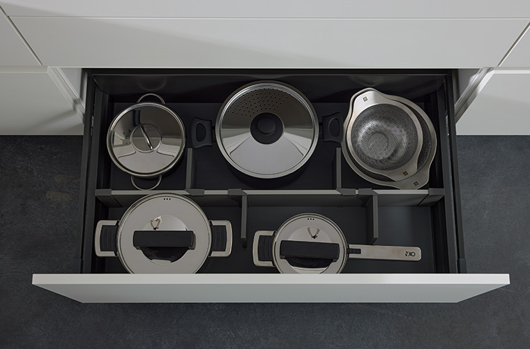 Eine geöffnete Schublade eines Küchenschranks mit Töpfen und Pfannen.