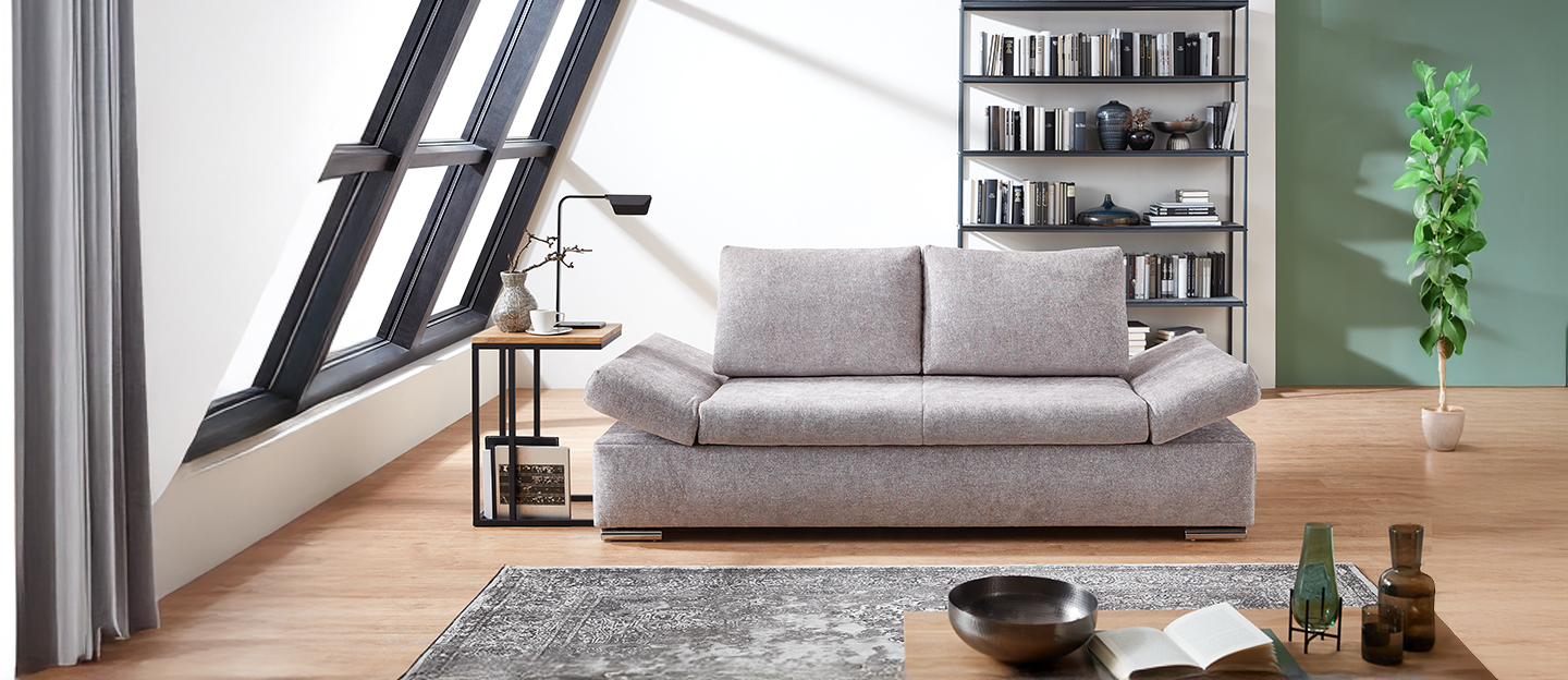 Modernes Wohnzimmer mit grauem Schlafsofa im Mittelpunkt.