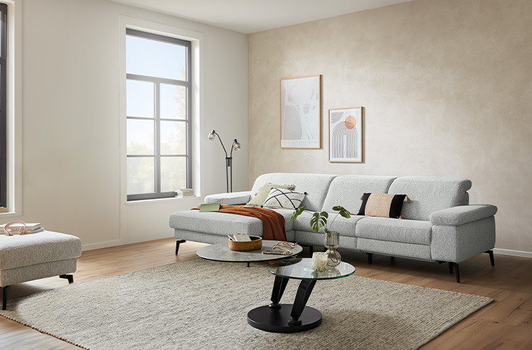 Helles Wohnzimmer mit einem grauen Ecksofa.