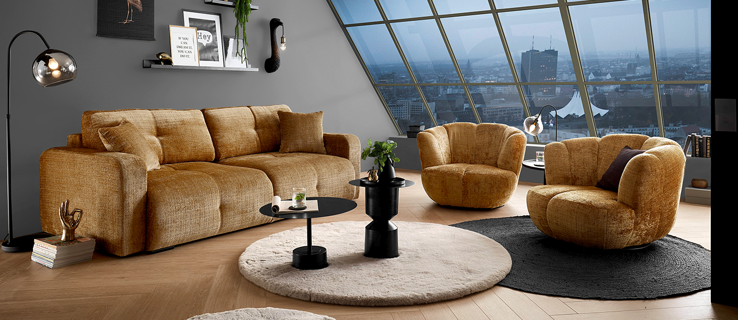 Senfgelbe Sitzgruppe bestehend aus zwei Sesseln und einem Sofa.