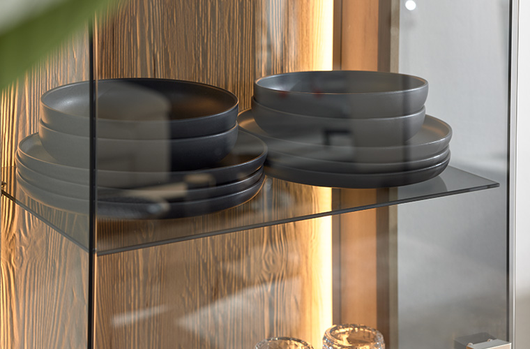 Beleuchtete Glasablage in einer Vitrine mit Holzdetails.