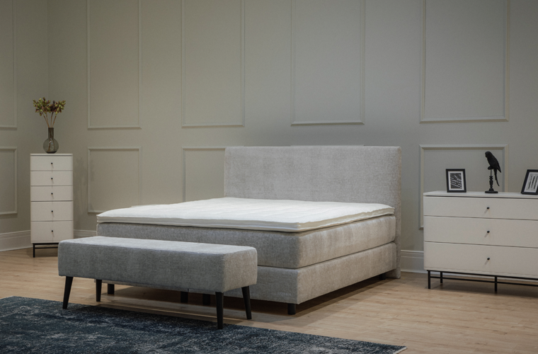 Bett „Hyrup“ mit hellgrauem Stoffbezug und hohem Kopfteil.