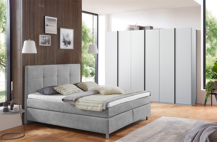 Polsterbett „Vera“ in hellgrauem Stoff mit gepolstertem Kopfteil.