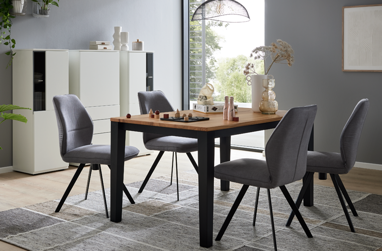 Essgruppe „IL 5102“ mit rechteckigem Tisch in Holzoptik und Metallbeinen sowie gepolsterten Stühlen in Grau.