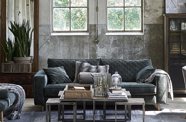 Wohnzimmer mit dunklem Sofa, Couchtisch und großen Fenstern.