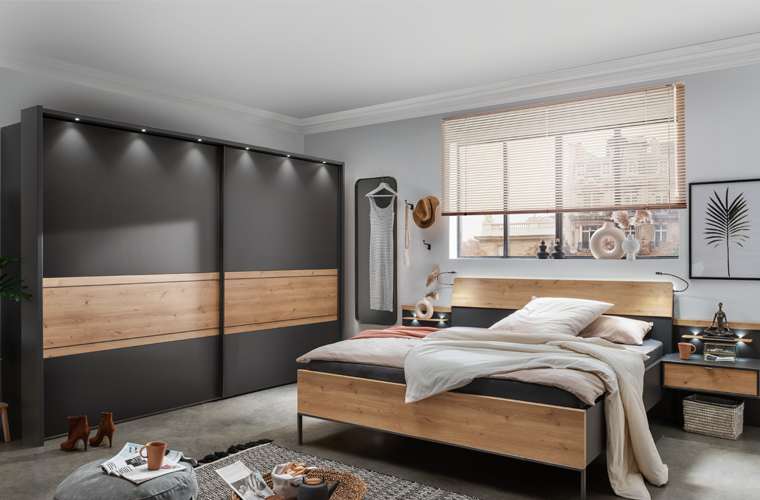Schlafzimmer „Lech“ mit dunklen Fronten und Holzoptik.