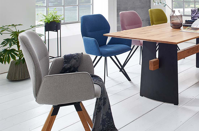 Moderner Essbereich mit Holztisch und gepolsterten Stühlen in verschiedenen Farben.