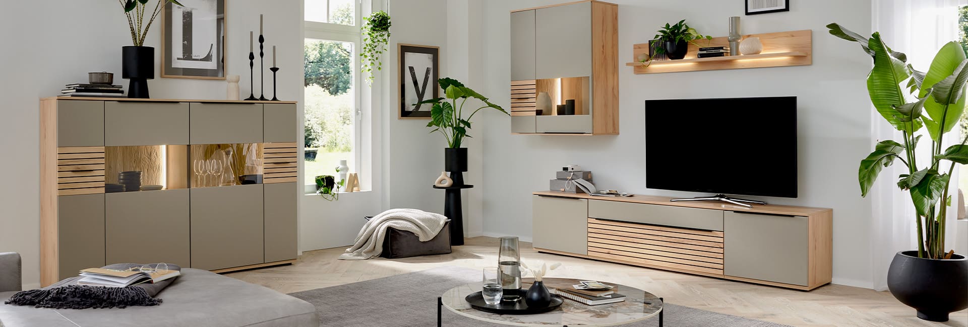 Wohnwand von Interliving in Holzoptik mit schwarzem Akzent in hellem Raum.