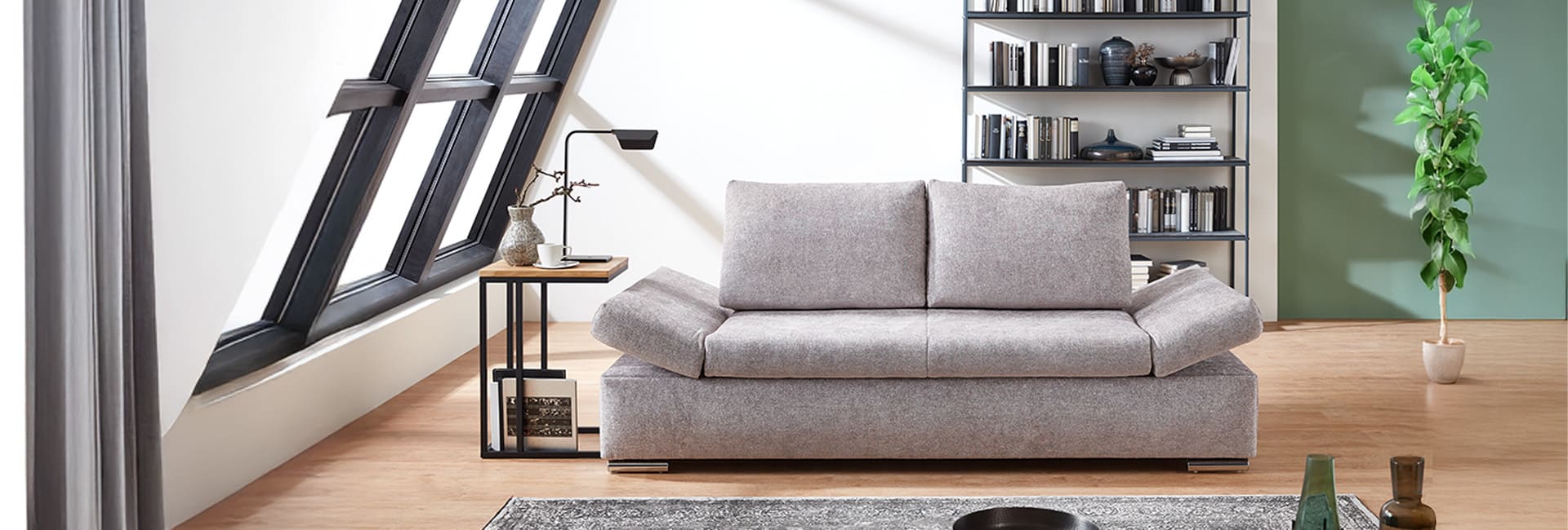 Modernes Wohnzimmer mit grauem Schlafsofa im Mittelpunkt.