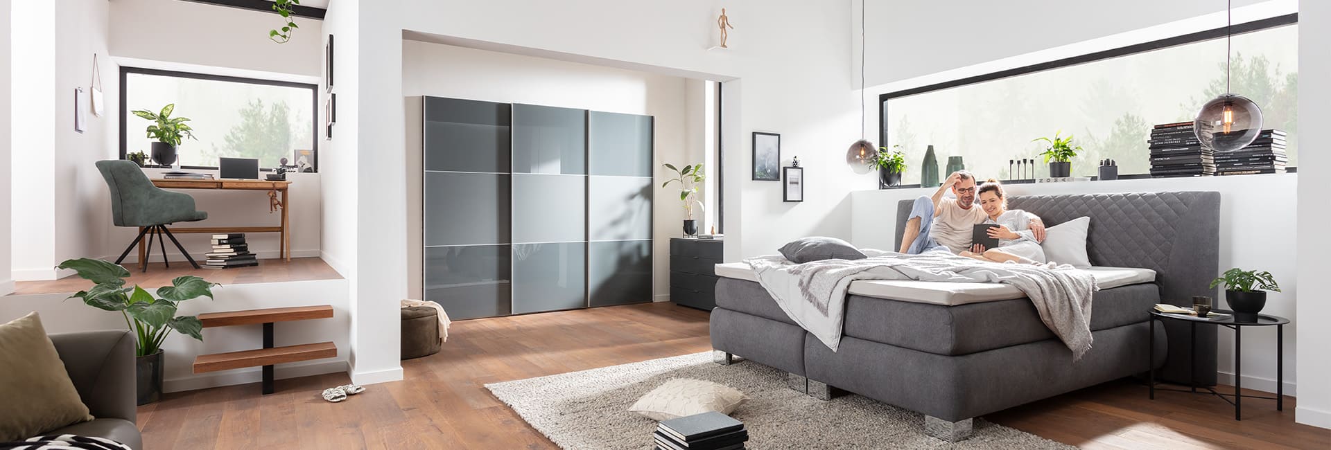 Graue Polstermöbel und dunkle Schränke in einem großen Raum.