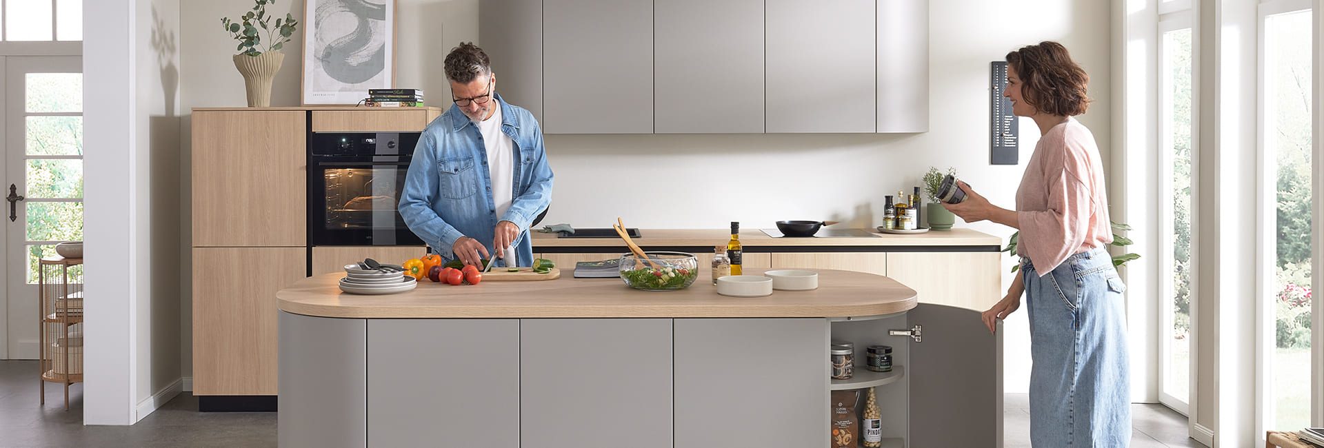 Paar kocht gemeinsam in einer modernen, hellen Küche.
